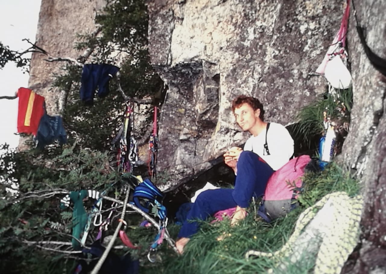 Frokost: Artikkelforfatteren nyter det som antagelig er en skive med brunost og honning, standard turmat på Kjerag på 90-tallet. Dette er om morgenen den skjebnesvangre dagen etter at han og Stein-Ivar Gravdal sov sånn passe godt i noen elendige hengekøyer. Fra dette punktet begynner den tunge klatringen og uhellet skjedde 2-3 taulengder høyere oppe. Fun fact: Paula Voldner ble hentet ut av RAR nedenfor pilaren bak dem i mai 2018, også hun etter beinbrudd, men langt mer alvorlig enn Sindres. Foto: Gravdal-arkiv